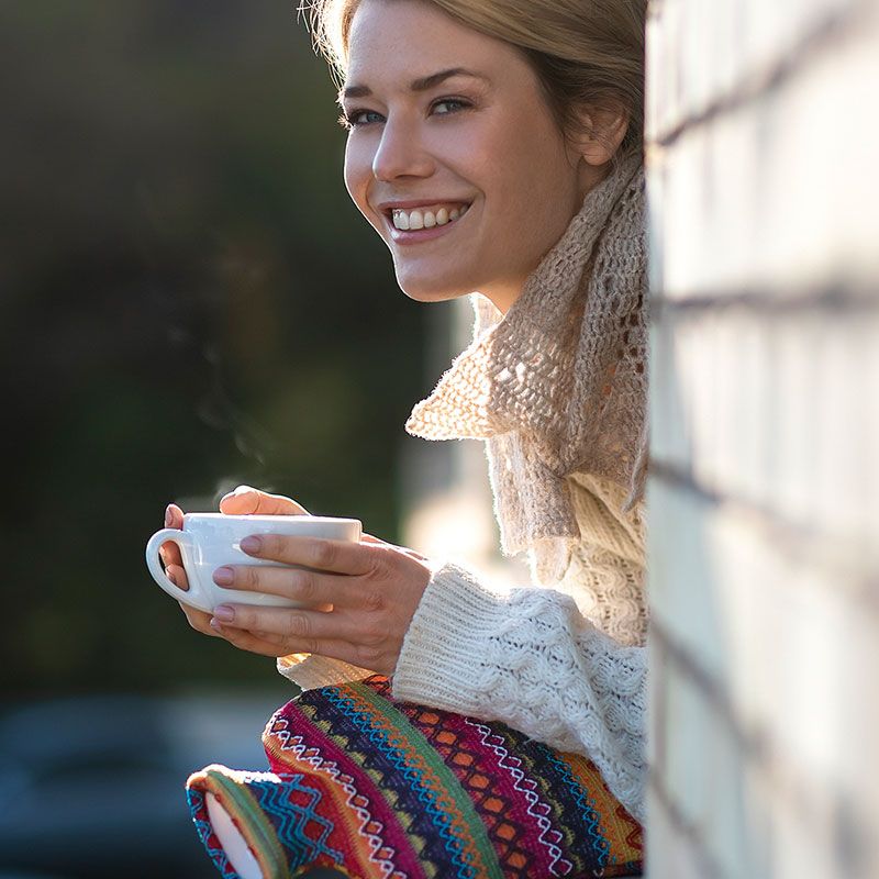 Frau mit einer Tasse Tee und Wärmflasche